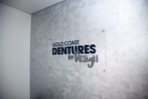 Dentures by Design logo on wall